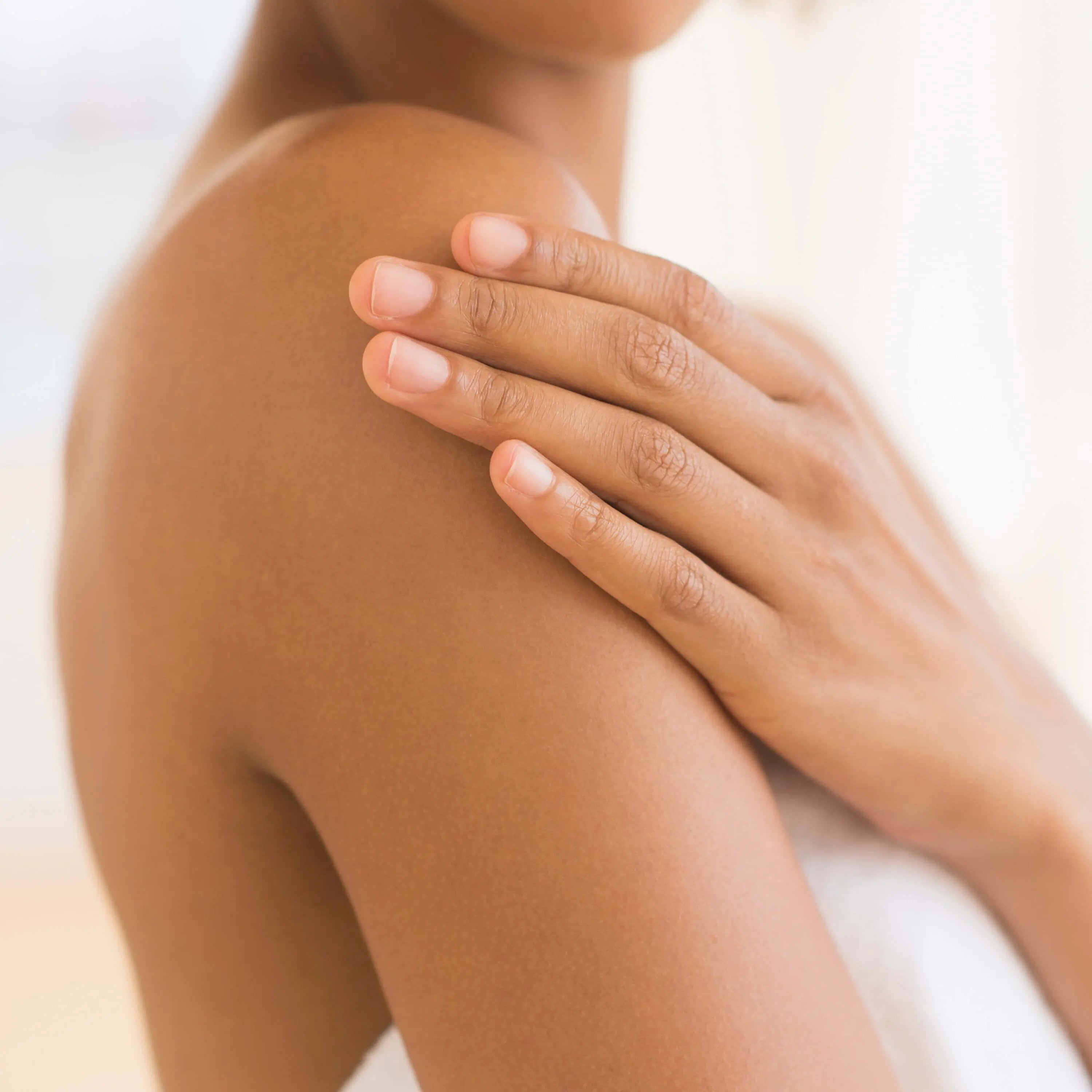 Olay Age Defying Body Wash bottle alongside a loofah and spa essentials
